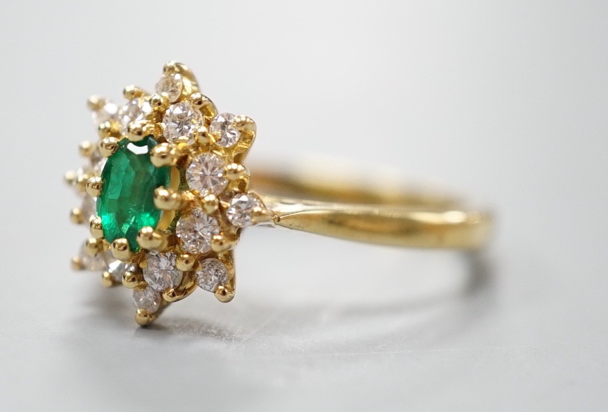 A modern 18ct gold, emerald and diamond set star shaped cluster ring, size L/M, gross weight 3.8 grams